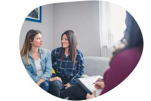 Two women sitting on couch speaking in front of counsellor
