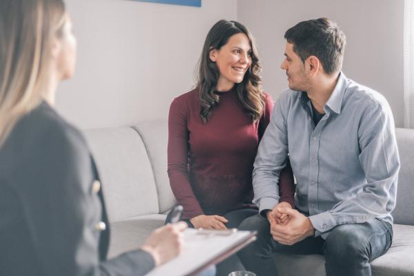 Counsellor taking notes as man and woman talking happily